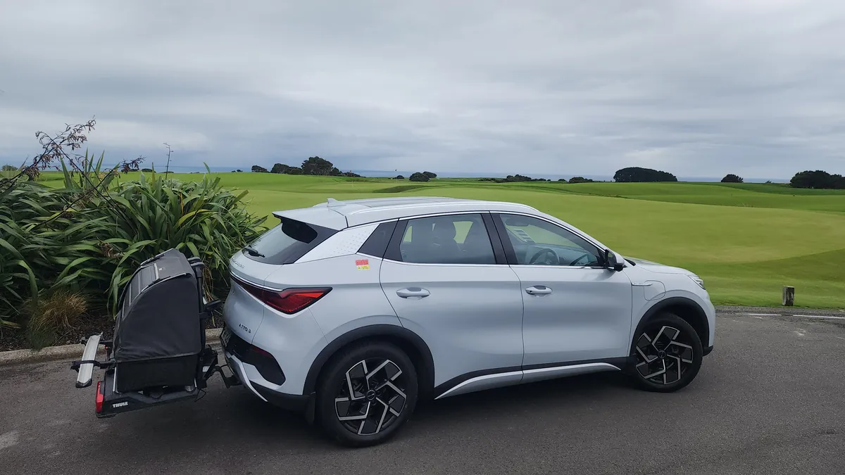 The fully electric BYD Atto 3 with a golf travel bag on its rear carrier beside the fairways at Cape Kidnappers