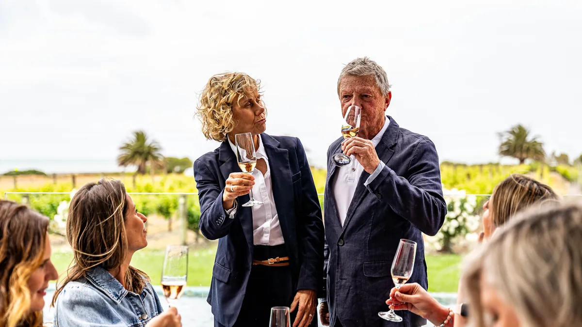 Guests sharing a glass of wine on a terrace above the vines at a Hawke's Bay winery