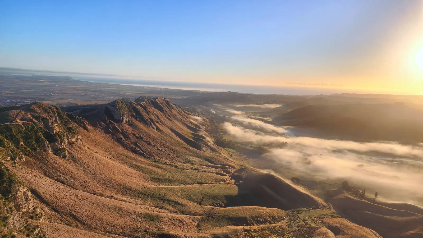 Sunrise over the ridgeline of Te Mata Peak, with morning cloud lying in the Tukituki Valley, Hawke's Bay