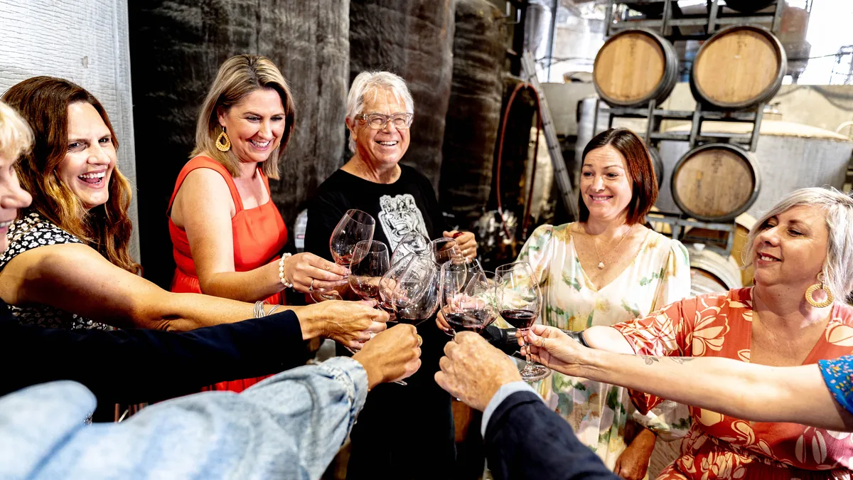 Guests raising their glasses at a tasting among the barrels on the Great Wine Capital Reserve tour in Hawke's Bay