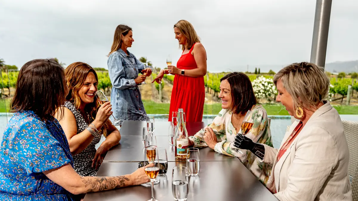Guests sharing a wine tasting at a terrace table above the vines on a hosted Hawke's Bay wine tour