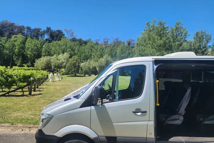 The Mercedes-Benz Sprinter waiting with its side door open beside a Hawke's Bay vineyard as the wedding party gathers
