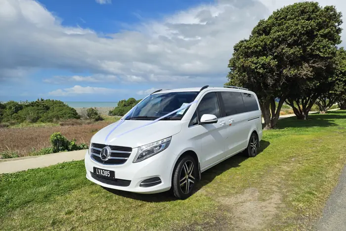 The Electric Executive Mercedes-Benz V-Class dressed with white wedding ribbon beside the Hawke's Bay coast